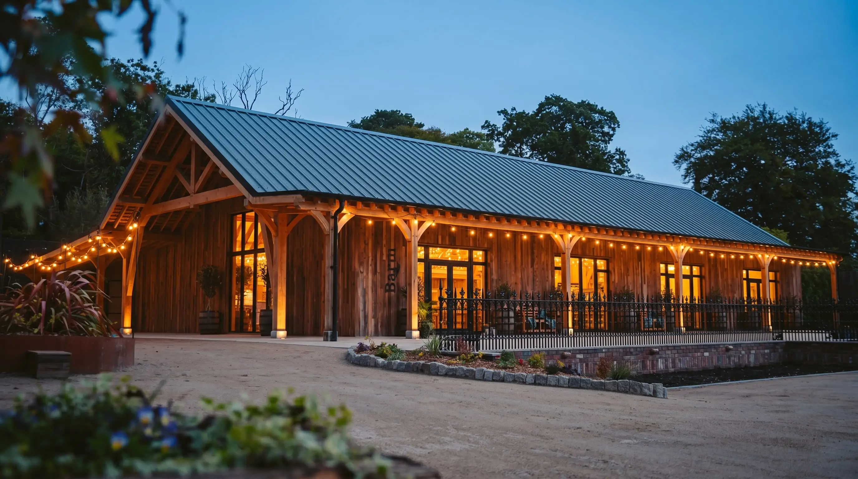 The Hideaway Barn at dusk, its windows and veranda festoon lights glowing