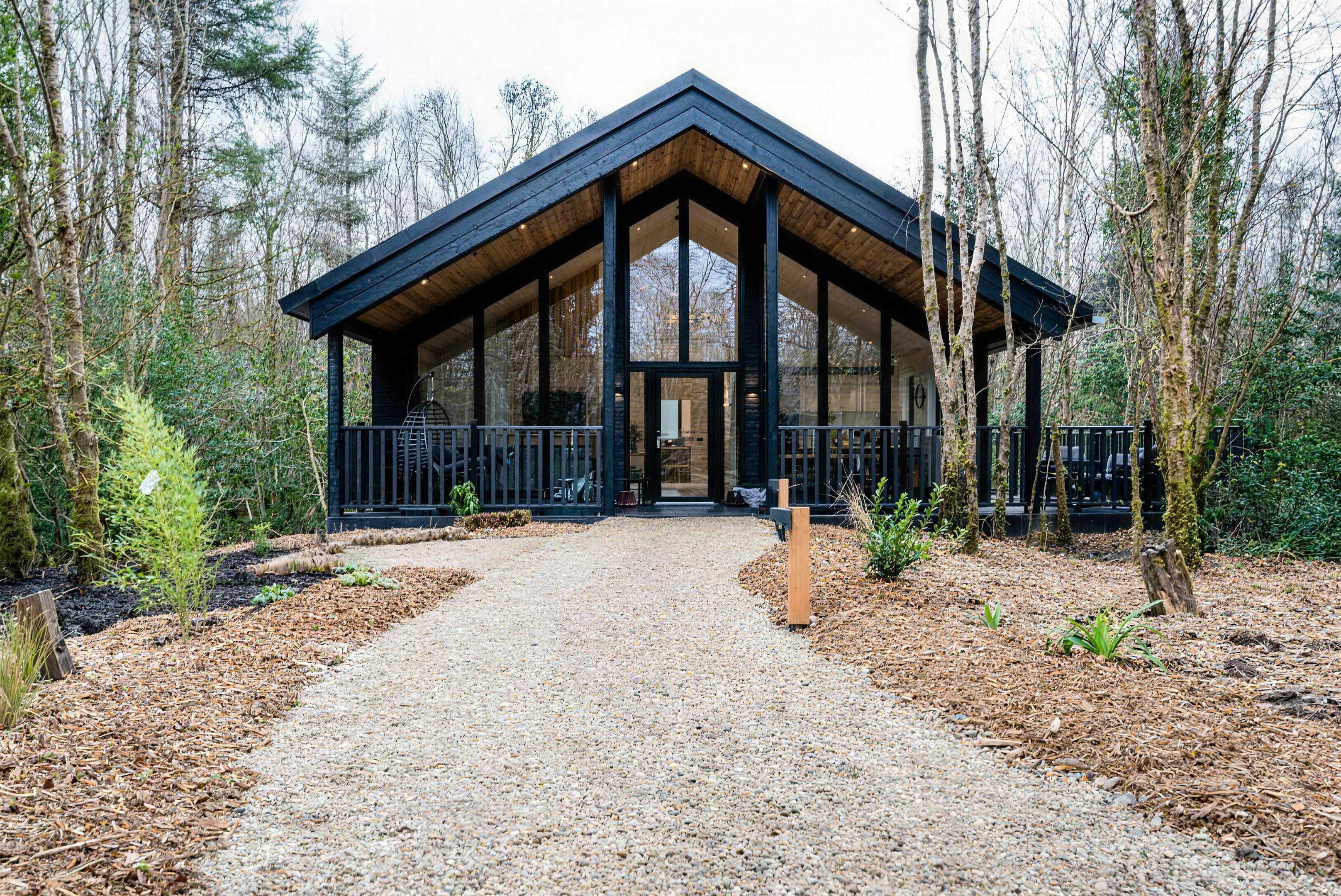A Birds of a Feather lodge — traditional pitched-roof cabin with a glazed front among the trees