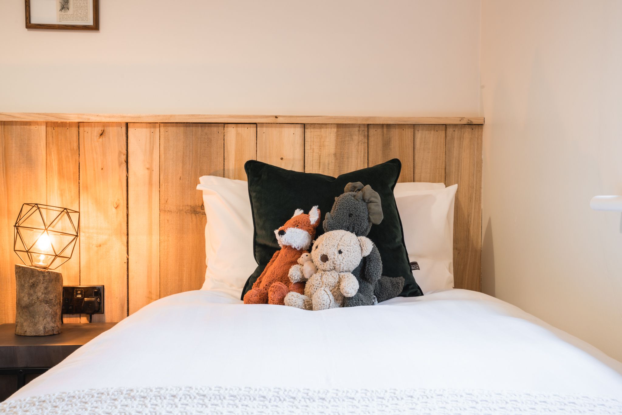 Bedroom dressed with lamplight and a woodland cushion