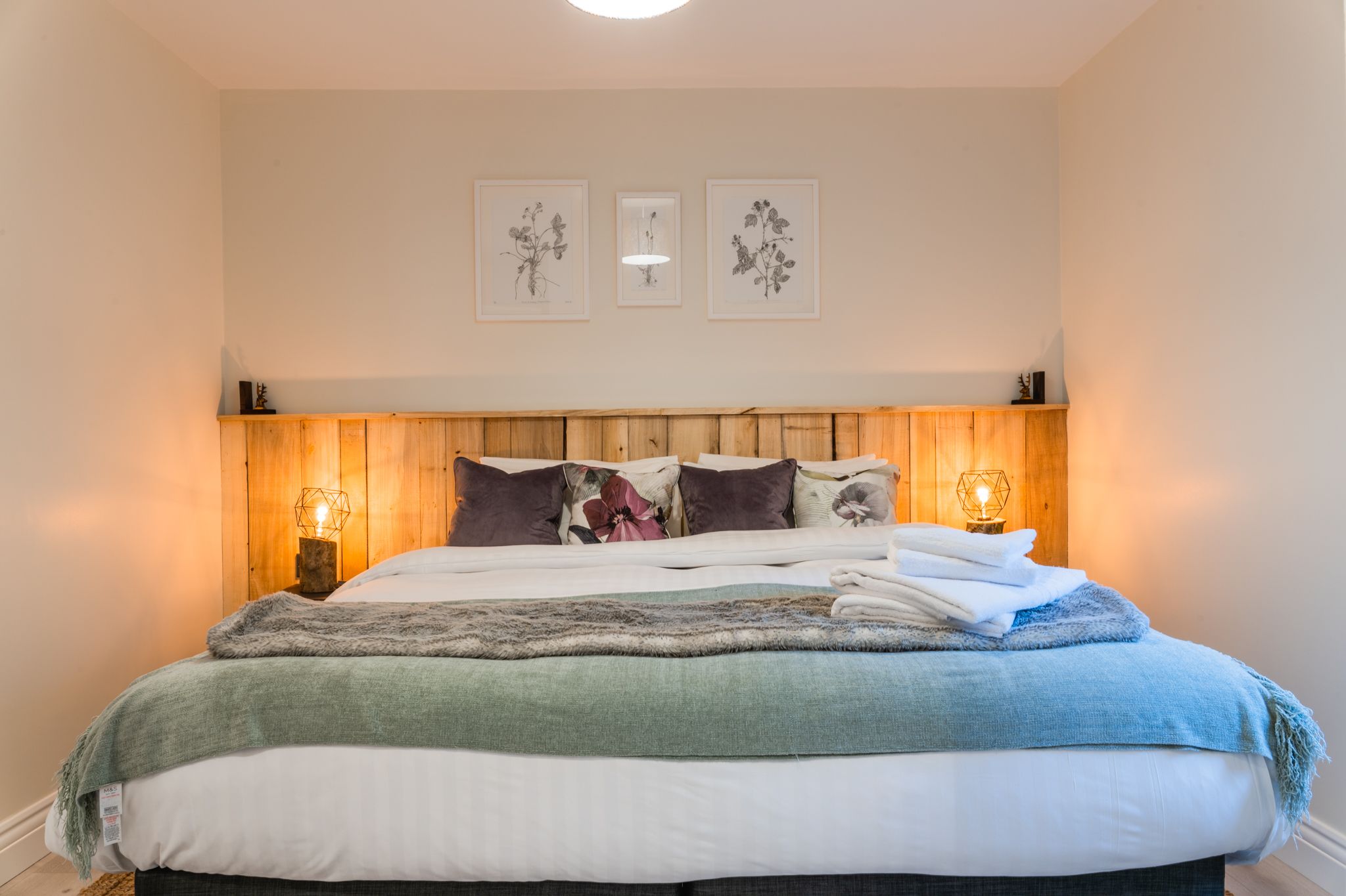 King bedroom with an estate-timber headboard and lamplight