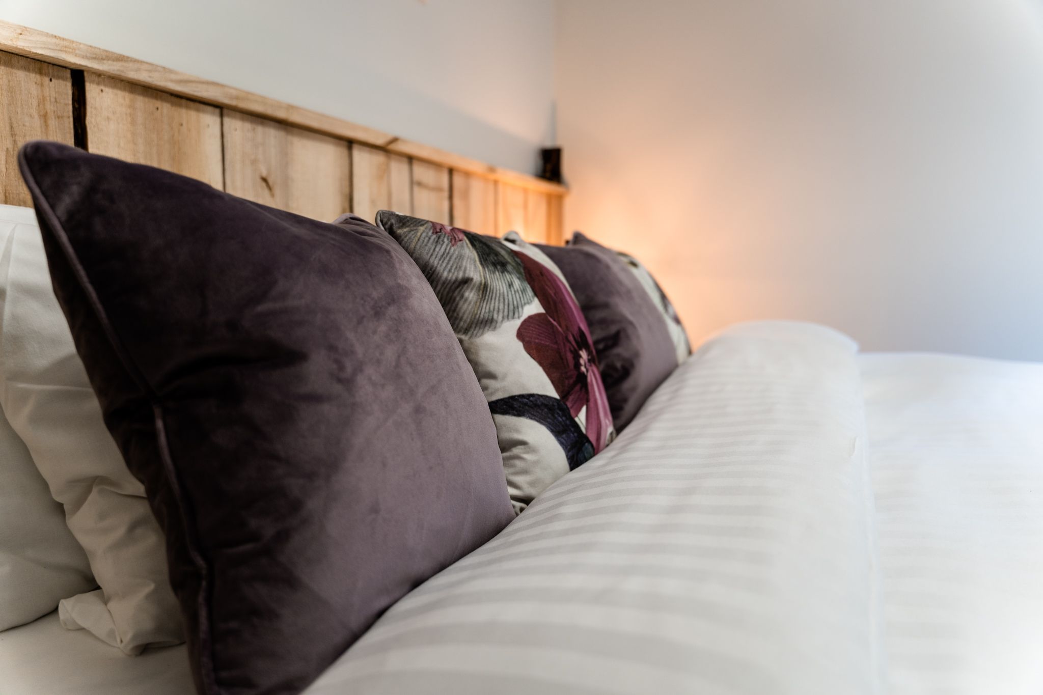 Bedroom with deep-green cushions and a timber headboard
