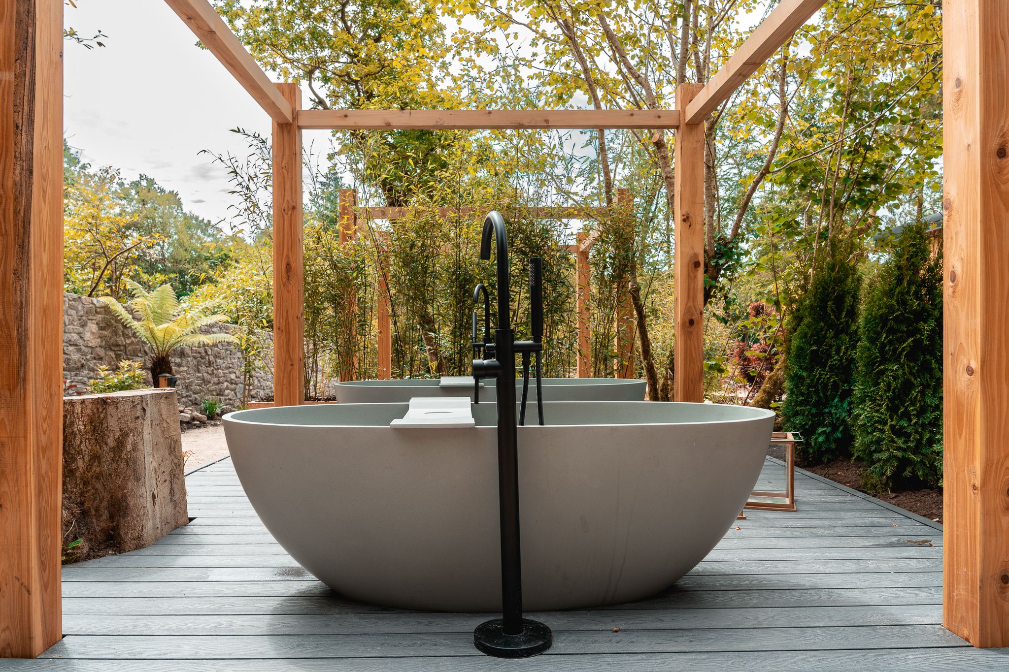 A stone bath under the timber pergola on the Sanctuary deck, the tap running
